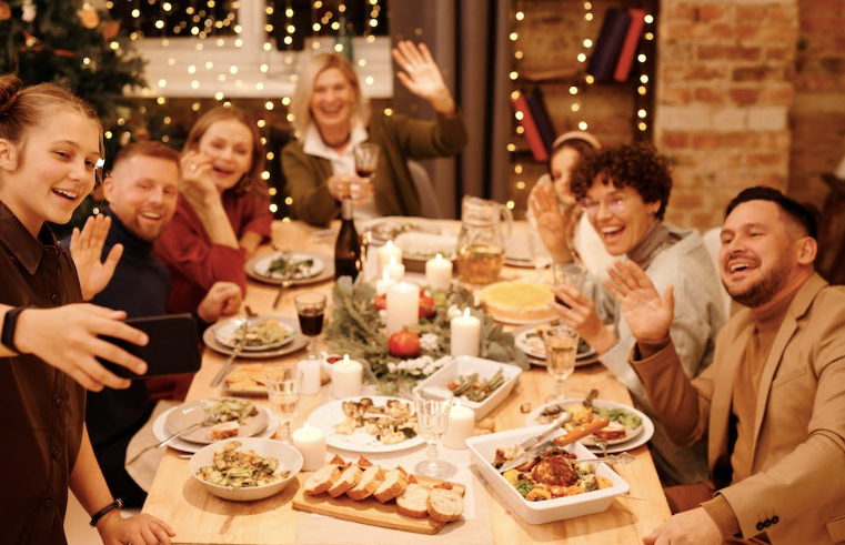 A group of people around a dining table celebrating the holiday, dressed in winter fashions.