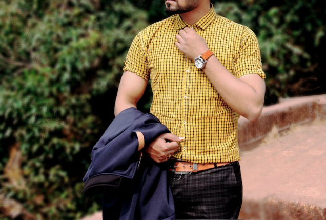 Fashionable man dressed in fitted button-down and jeans carrying a casual jacket over his arm.