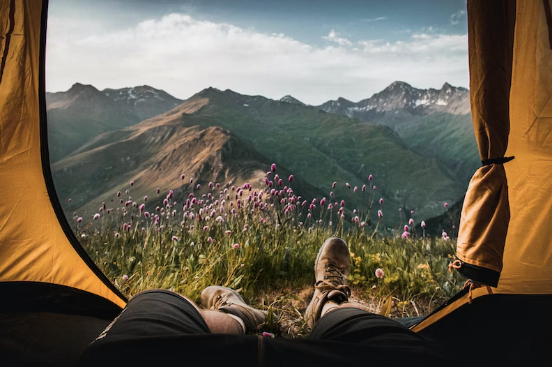 View of a summer mountain landscape from inside a yellow tent.